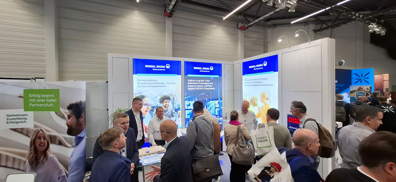 Menschen auf der VEMA Messe am Stand von SIGNAL IDUNA
